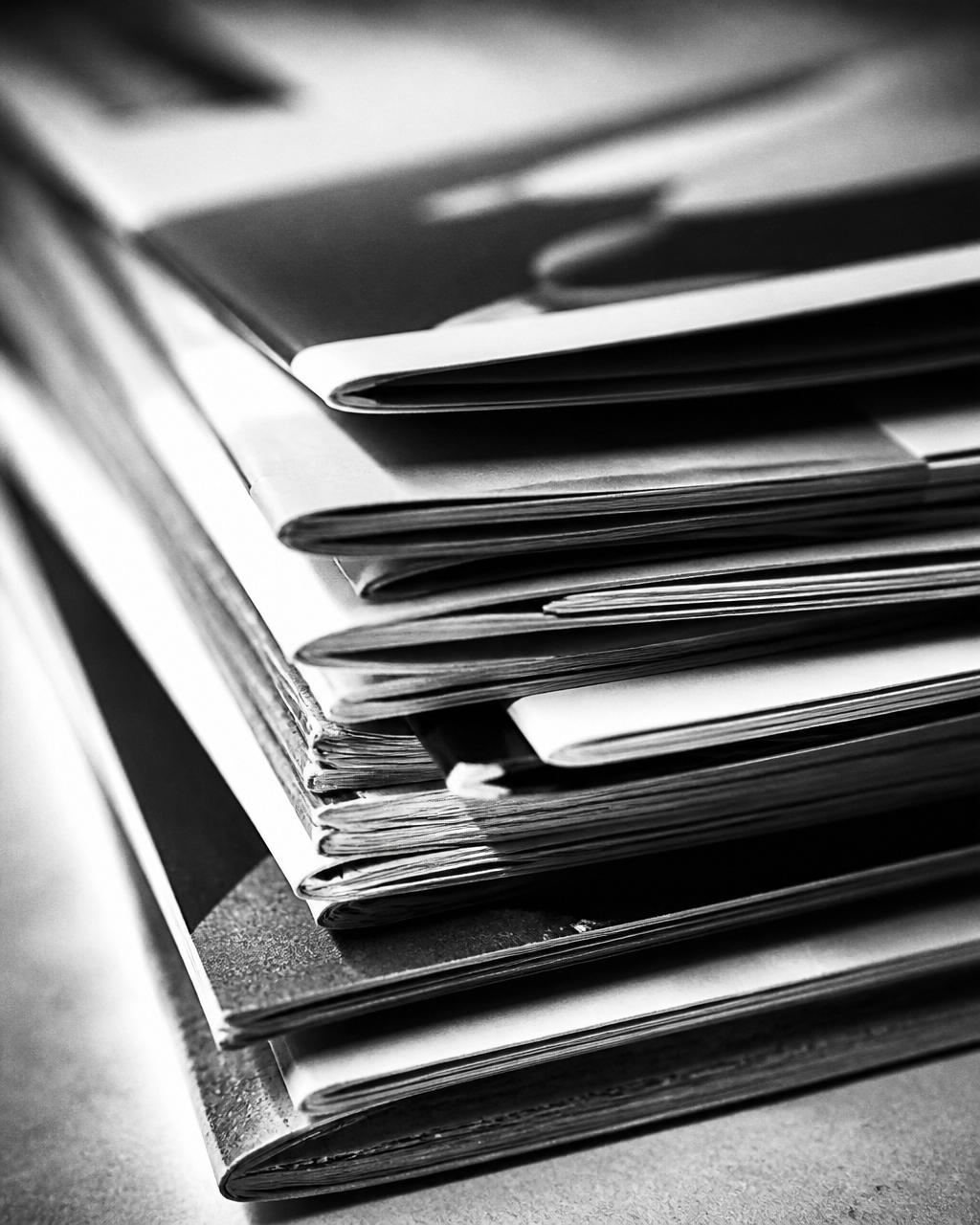 Close up stack of printed brochures and mailers in monochrome